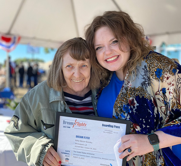 senior woman and younger woman smiling for the camera while holding a Dream Flights envelope