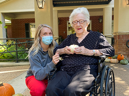 caregiver and senior woman in a wheelchair smiling at the camera